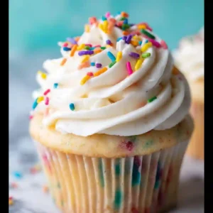 Two frosted cupcakes on plates with a piping bag filled with dairy free icing beside them