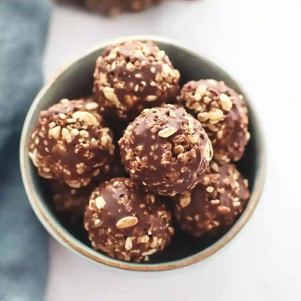 A light blue bowl piled high with homemade treats from the Chocolate Rice Krispie Balls Recipe, shown from a side angle.