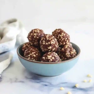 A detailed close-up of one finished treat, showing the texture of the Chocolate Rice Krispie Balls Recipe, with the serving bowl blurred in the background.