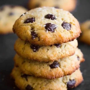 A close-up stack of four soft coconut flour chocolate chip cookies showing golden brown edges and melted chocolate chunks