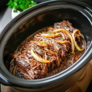 An oval Slow Cooker filled with a cooked French Onion Roast, featuring melt-in-your-mouth beef chuck and savory onions ready to be served