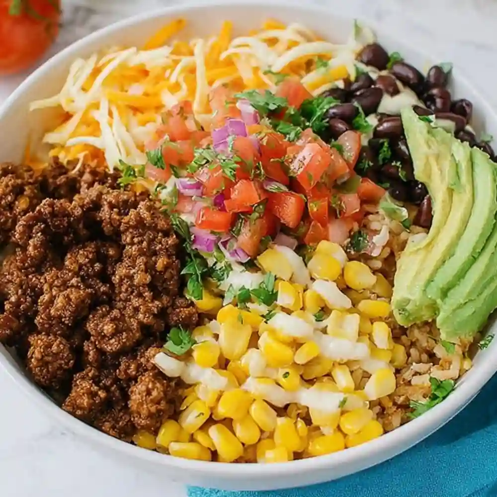 Sautéed ground beef, charred corn, and black beans in a skillet for a taco bowl base.
