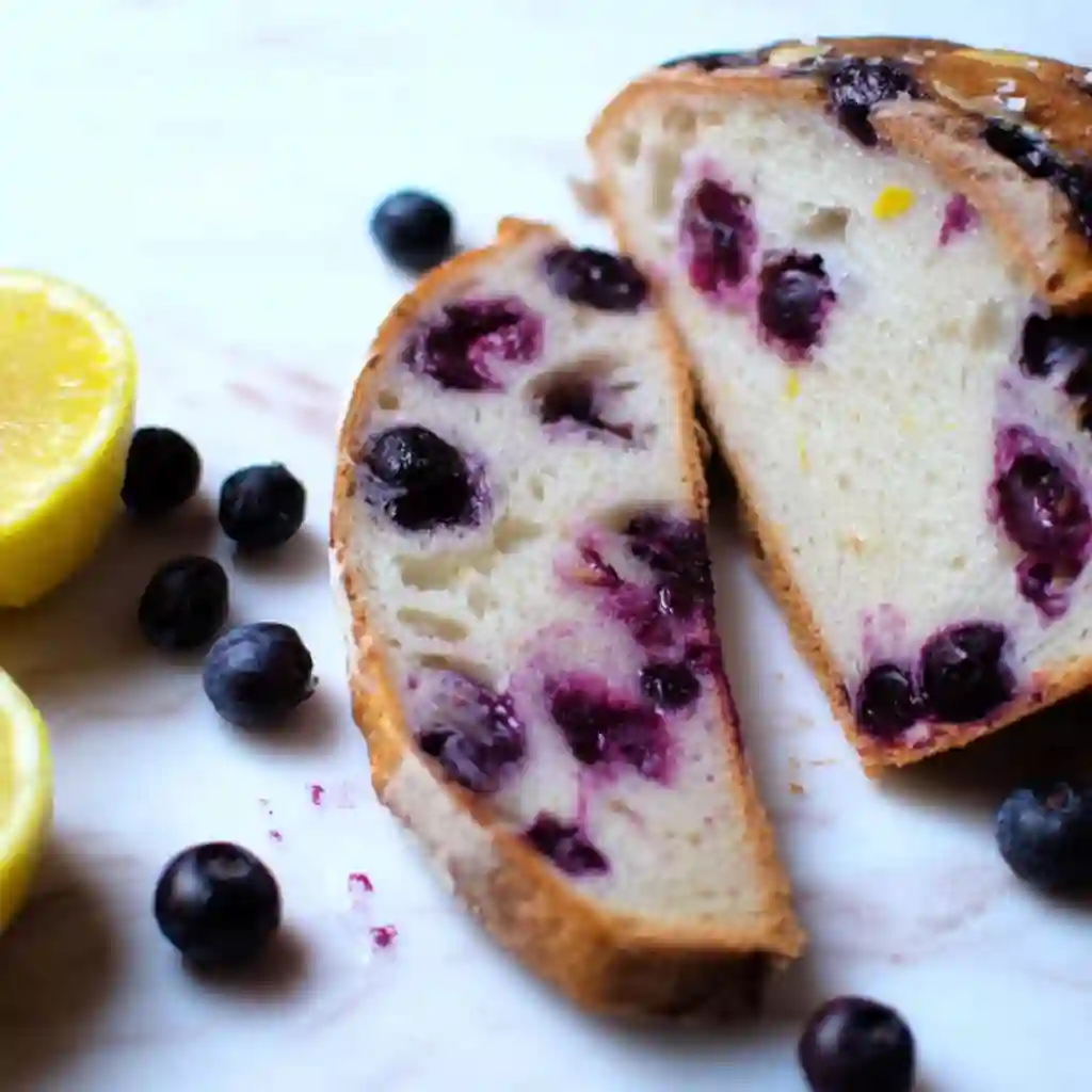 Mixing fresh blueberries and lemon zest into a Lemon Blueberry Sourdough Bread dough during stretch and folds.
