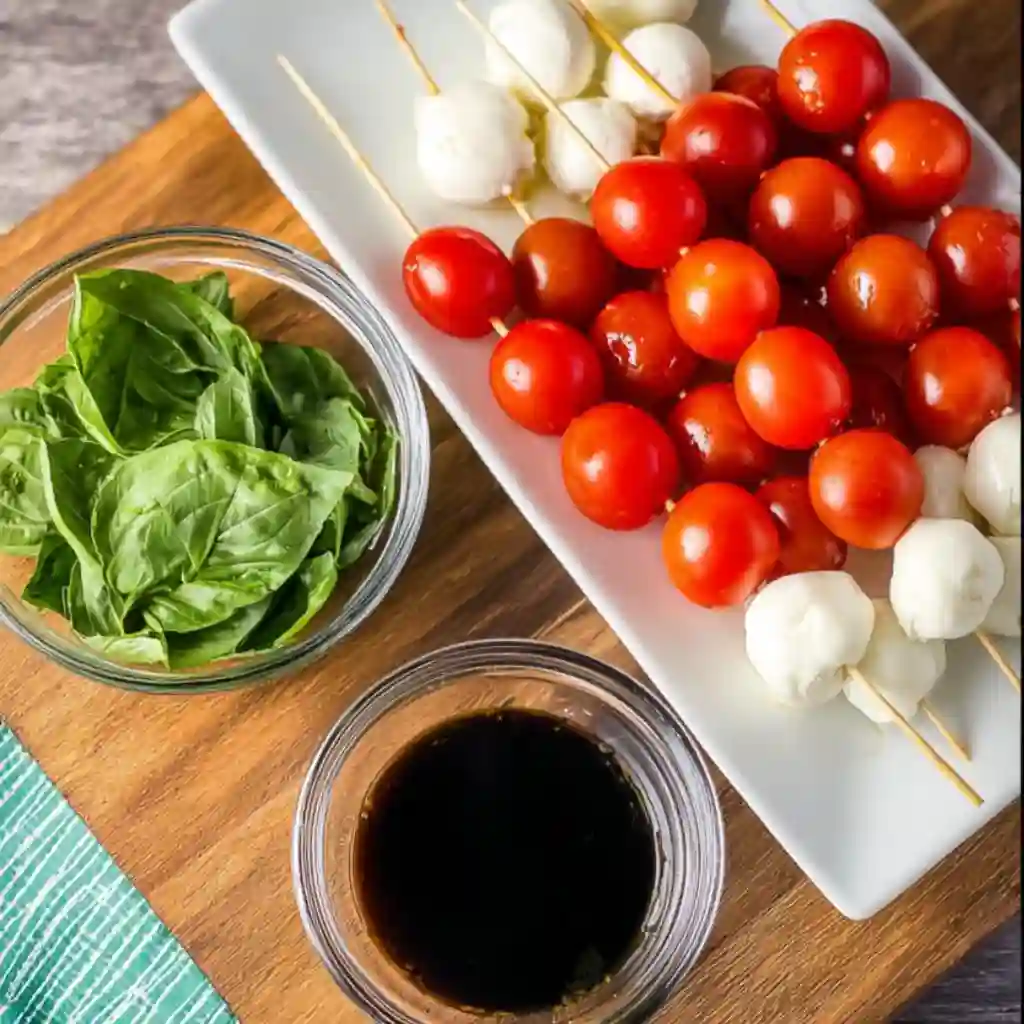 Fresh ingredients for Caprese Skewers including cherry tomatoes, mozzarella balls, and fresh basil leaves.