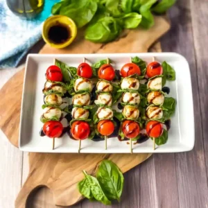 Balsamic reduction being drizzled over a tray of ready-to-eat Caprese Skewers.