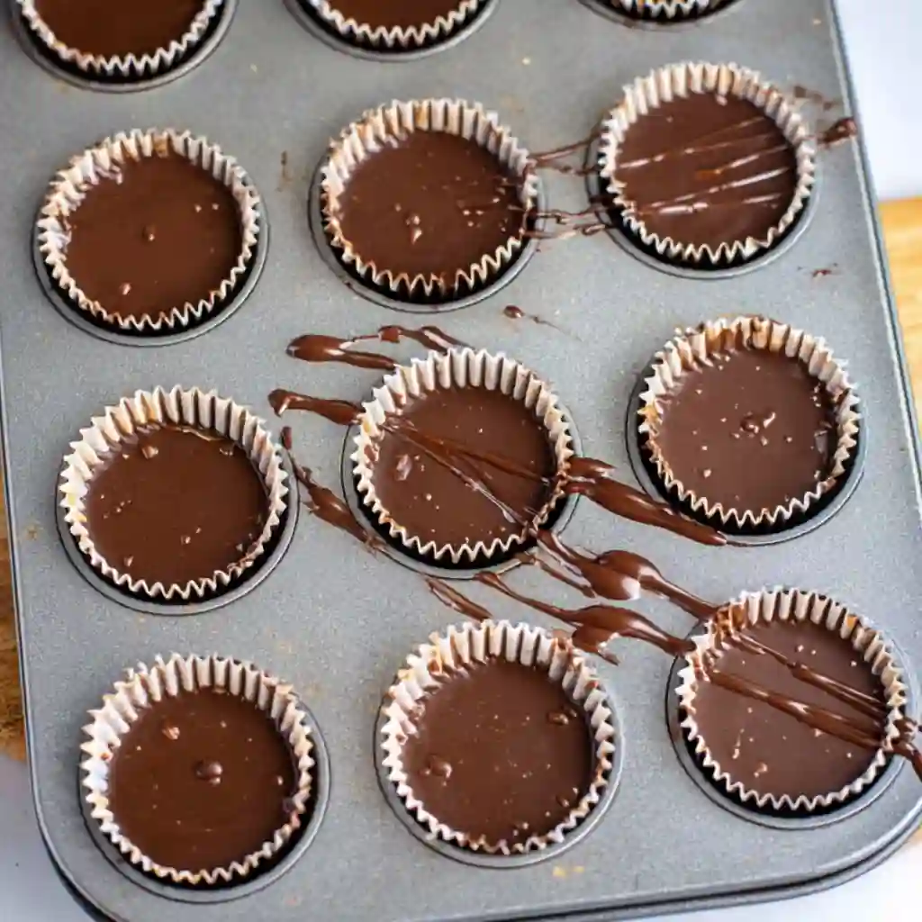 Brushing melted chocolate into cupcake liners to make Homemade Reeses Cups.
