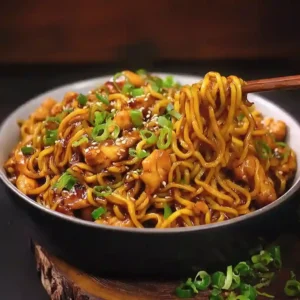 Searing chicken pieces in a wok to make Sticky Garlic Chicken Noodles.