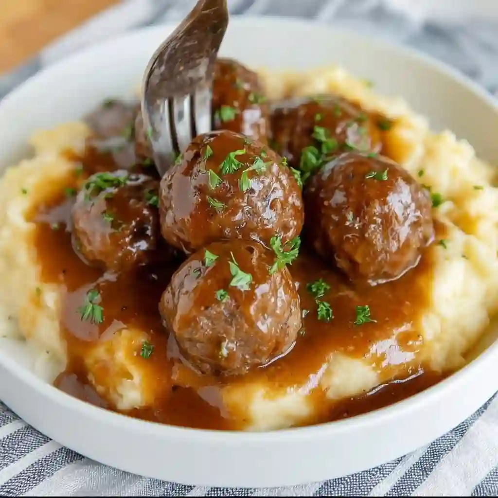  Close-up of Salisbury steak meatballs with mushroom gravy over mashed potatoes.
