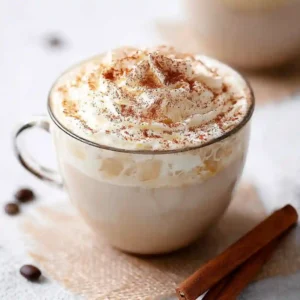 A tall glass of iced vanilla cinnamon latte with layers of milk and coffee.