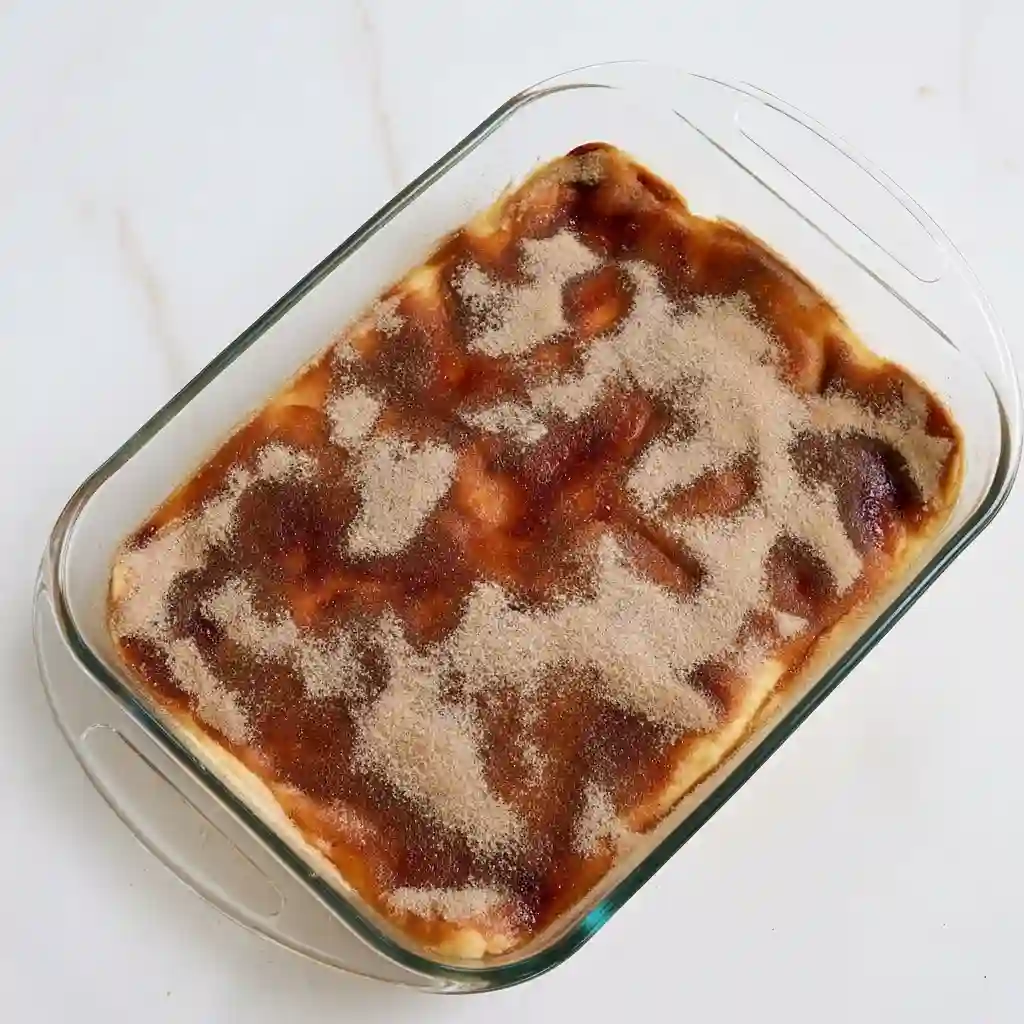 Stack of three golden brown Churro Cheesecake bars coated in cinnamon sugar on a white plate.