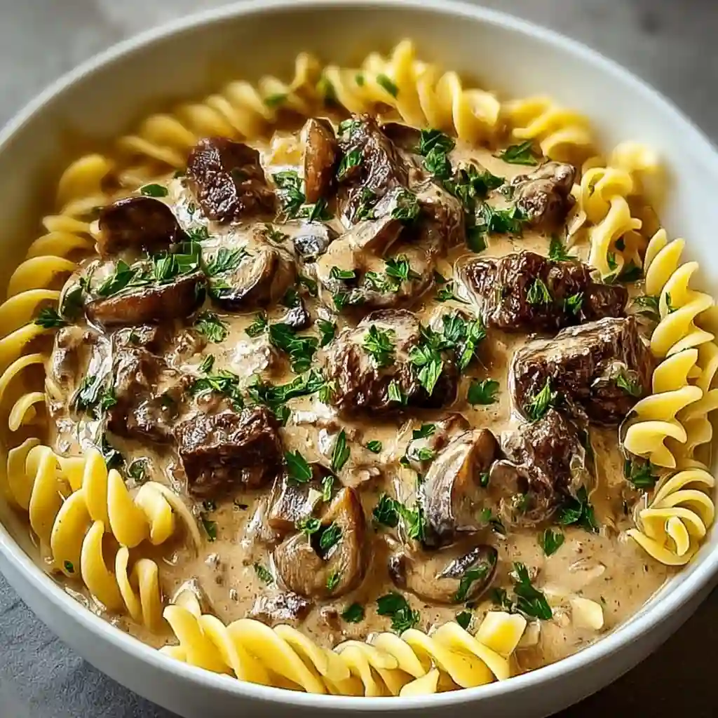 Fork lifting creamy beef stroganoff noodles with savory mushroom sauce.
